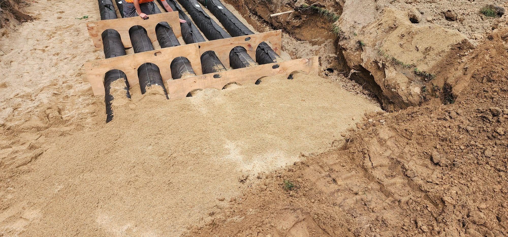 Drain field chambers aligned with wooden spacers during backfill