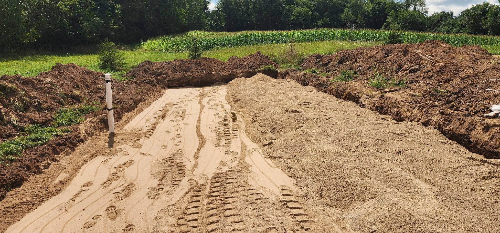 Leveled sand bed prepared for a septic drain field with a monitoring pipe